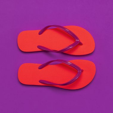 Mor arka planda mercan parmak arası terlik. Düz döşeme, üst görünüm, kopyalama alanı. Yaratıcı Yaz Tatili seyahat Arka Plan. Kadınların yazlık ayakkabısı. Parlak parmak arası terlikler, trend renkler