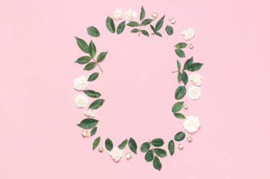 Çiçeklerin Çerçevesi kompozisyonu. Yumuşak pembe arka plan üzerinde beyaz taze gül ve yeşil yaprakları. Düz döşeme, üst görünüm, kopyalama alanı. Çiçek kartı, selamlama, tatil maketleri. Sevgililer Günü arka plan kadınlar günü