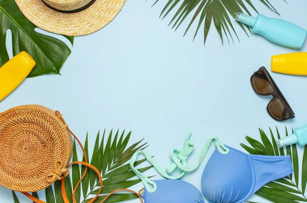Summer composition flat lay. Frame of Round trendy rattan bag straw hat sunglasses tropical palm leaves swimsuit sunscreen seashells on blue background. Top view copy space. Creative fashion backdrop — Stock Photo, Image