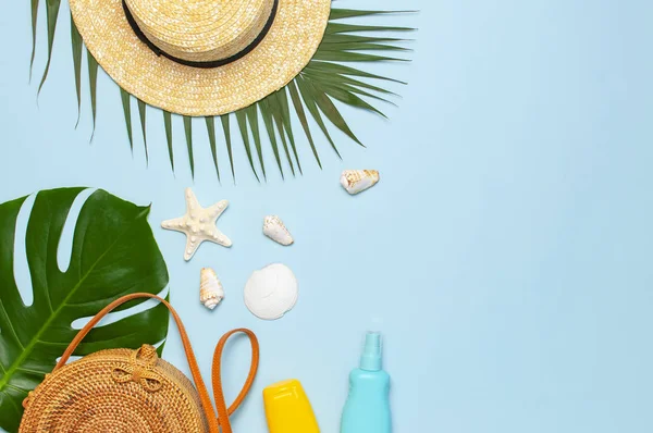 Composición de verano plano laico. Bolso de ratán redondo de moda sombrero de paja palma tropical hojas de coco protector solar conchas marinas sobre fondo azul. Espacio de copia de vista superior. Fondo de vacaciones de moda creativa — Foto de Stock