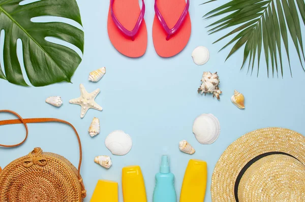 Composición de verano plano laico. Bolso de ratán de moda redondo sombrero de paja chanclas de coral hojas de palma tropical protector solar de coco conchas marinas sobre fondo azul. Espacio de copia de vista superior. Fondo de moda creativa — Foto de Stock