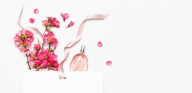 Şişe kadın parfüm ile pembe bahar çiçekler beyaz hediye paketi üzerinde ışık arka plan üst görünüm düz yatıyordu kopya alanı. Parfümeri kozmetik kadın aksesuarları koku koleksiyonu. Parfüm şişesi
