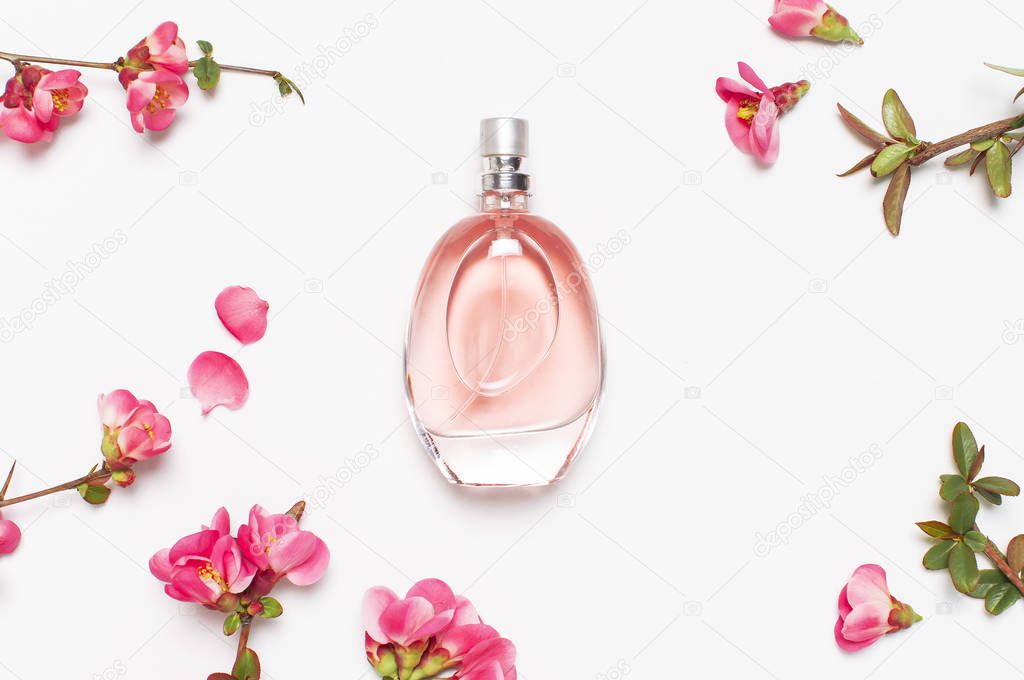 Bottle of womens perfume with pink spring flowers on light gray background top view flat lay copy space. Perfumery, cosmetics, female accessories, fragrance collection. Delicate Pink Perfume Bottle