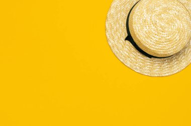 Kadın yaz saman şapka sarı arka plan üst görünümü düz kopya alanı yatıyordu. Yaz seyahati tatil konsepti, tek öğe. Kadın aksesuarı, yaz arka planı
