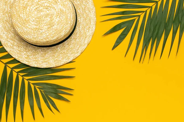 Women s summer straw hat, tropical palm leaves, monstera leaf on yellow background top view flat lay copy space. Summer travel vacation concept. Female accessory, summer background — Stock Photo, Image