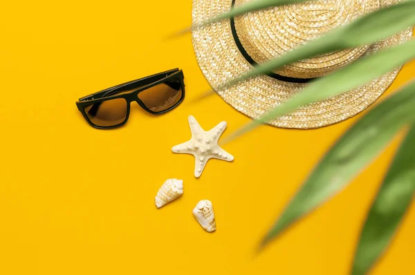 Women s summer straw hat, tropical palm leaves, monstera leaf, sunglasses, shells, starfish on yellow background top view flat lay copy space. Summer travel vacation concept. Female accessory, summer — Stock Photo, Image