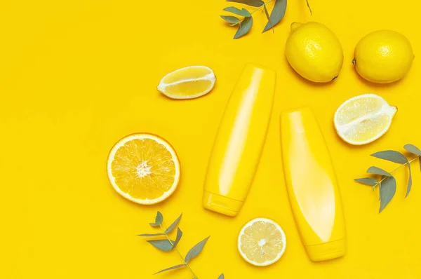 Sarı Kozmetik şişe kapları, limon, turuncu, okaliptüs sarı arka planda düz görünüm fotokopi alanı. Marka modeli için boş etiket Doğal güzellik ürünü güneş kremi yaz konsepti — Stok fotoğraf