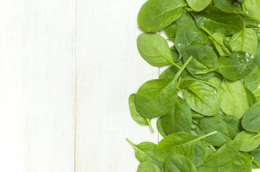 Taze yeşil ıspanak üzerinde beyaz ahşap rustik arka plan üstten görünüm kopya alanı bırakır. Bebek Genç ıspanak yaprakları, salata, sağlıklı gıda, diyet için madde. Beslenme kavramı.