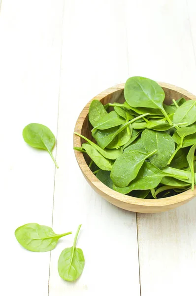 Fresh green spinach leaves on wooden bowl on white wooden rustic background top view copy space. Baby young spinach leaves, Ingredient for salad, healthy food, diet. Nutrition concept. — Stock Photo, Image