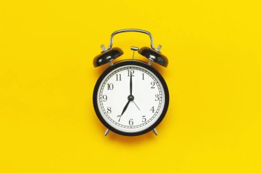 Sarı arka plan en iyi görünüm düz siyah retro çalar saat kopya alanı yatıyordu. Minimalist arka plan, zaman, son tarih, çalışmak için zaman, sabah kavramı