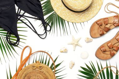 Kadının plaj aksesuarları düz yatıyordu. Yuvarlak trendy rattan çanta hasır şapka siyah mayo deri sandalet tropikal palmiye beyaz arka plan üzerinde deniz kabukları bırakır. En iyi görünüm kopyalama alanı. Yaz arka planı