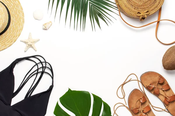 Accesorios de playa de mujer plana laico. Bolso de ratán de moda redonda sombrero de paja traje de baño negro sandalias de cuero hojas de palma tropical conchas de coco sobre fondo blanco. Espacio de copia de vista superior. Fondo de verano — Foto de Stock