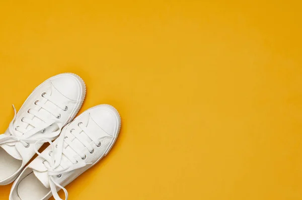 Sarı turuncu arka plan üzerinde beyaz kadın moda spor ayakkabıları. Düz lay üst görünüm kopyalama alanı. Kadın ayakkabıları. Şık beyaz spor ayakkabılar. Moda blog veya dergi kavramı. Minimalist ayakkabı arka plan, spor — Stok fotoğraf