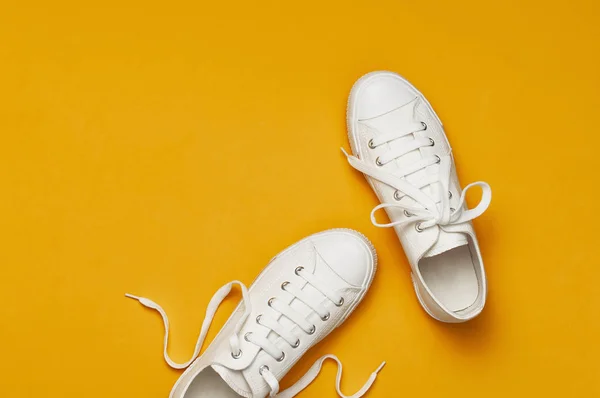 Белые модницы на желто-оранжевом фоне. Плоское пространство для копирования сверху. Женская обувь. Стильные белые кроссовки. Модный блог или концепция журнала. Фон обуви, спорт — стоковое фото