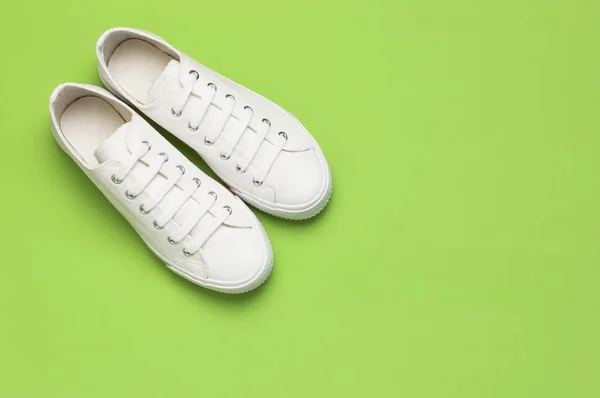 Білі кросівки жіночої моди на зеленому тлі. Плоский простір копіювання зверху. Жіноче взуття. Стильні білі кросівки. Модний блог або концепція журналу. Мінімалістичний фон взуття, спортивне взуття — стокове фото