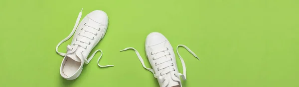 Witte vrouwelijke mode sneakers op groene achtergrond. Flat lay bovenaanzicht kopieerruimte. Vrouwenschoenen. Stijlvolle witte sneakers. Mode blog of tijdschrift concept. Minimalistische schoen achtergrond, sport schoenen — Stockfoto