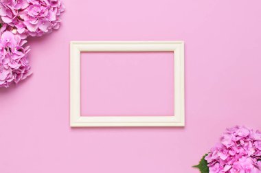 Güzel pembe ortanca çiçekler, pembe arka plan üst görünüm düz üzerinde beyaz ahşap fotoğraf çerçeveleri kopyalama alanı yatıyordu. Çiçek kartı. Tatil, tebrikler, mutlu anneler günü. Dünya Kadınlar Günü.