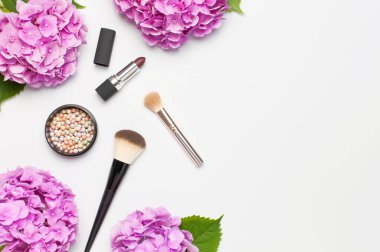 Dekoratif kozmetik makyaj fırçaları seti, allık yüz topları, hafif arka plan üst görünümü Düz renkli pembe ortanca çiçekler kopya alanı yatıyordu. Güzellik blogger kavramı. Moda arka plan