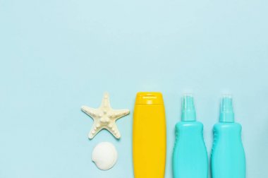 Yaz konsepti, deniz geçmişi. Deniz kabukları, denizyıldızı, pastel mavi arka plan üzerinde güneş kremi vücut kremi sprey. Üst görünüm, düz döşeme, kopyalama alanı. Deniz yaz tatili Mockup. Seyahat, deniz hatırası