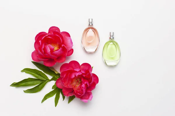 Perfume bottles and pink flowers peonies on light gray background top view Flat lay copy space. Perfumery, cosmetics, female accessories, fragrance collection. Delicate Perfume Bottle.