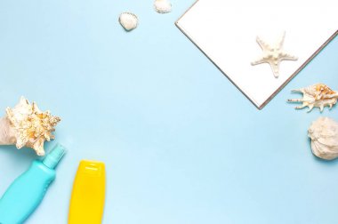Yaz konsepti, deniz geçmişi. Deniz kabukları, denizyıldızı, beyaz boş çarşaf, mavi arka plan üzerinde güneş kremi vücut spreyi. Üst görünüm, düz döşeme, kopyalama alanı. Deniz yaz tatili Mockup. Seyahat, deniz hatırası.