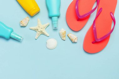 Yaz plaj deniz aksesuarları. Mercan parmak arası terlik, kabukları, denizyıldızı, sarı güneş kremi şişesi, mavi arka plan üst görünüm düz vücut spreyi kopyalama alanı yatıyordu. Yaz arka plan Tatil tatil seyahat konsepti