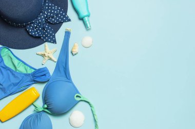 Yaz plaj deniz aksesuarları. Coral flip flop denim şort kadın hasır şapka kabukları denizyıldızı güneş kremi şişe vücut spreyi mavi arka plan üst görünümü düz yatıyordu. Yaz geçmişi. Tatil seyahat konsepti