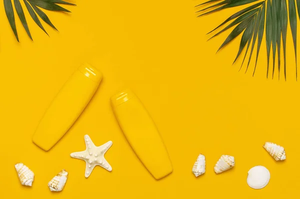 Yellow bottles of sunscreen cream, tropical palm leaves, shells, starfish on bright yellow background top view flat lay copy space. Sun protection. Summer background, vacation, travel concept — Stock Photo, Image