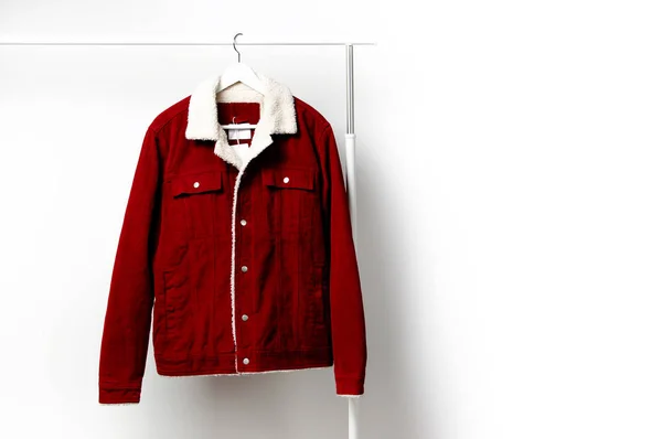Червоний кордуровий чоловічий піджак на вішалці для білого пальто на стрижні проти світлої стіни плоский простір для копіювання. Чоловіча мода, осіннє весняне пальто, молодіжний хіпстерський одяг стильна річ джинсова модна куртка, продаж магазину — стокове фото