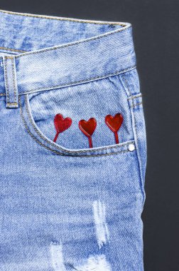 Mavi kot ve kırmızı kalpler cebinde siyah arka plan üst görünümü düz yatıyordu. Güzel mavi kot detay. Kot doku veya Denim arka plan. Trend Giyim. Moda, giyim konsepti, kot aşk