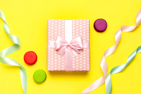 Geschenk-oder Geschenkbox, schöne festliche Schleife, Kuchen Macaron oder Makronen auf gelbem Hintergrund Draufsicht. flache Liegekomposition für Feier, Feiertag, Geburtstag, Valentinstag, 8. März, Muttertag — Stockfoto