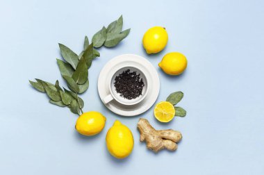 Creative food concept. Fresh ginger root, cup tea with brewing inside, lemon, eucalyptus leaves on blue background. Flat lay top view copy space. Minimalistic style seasoning spice ingredient for tea clipart