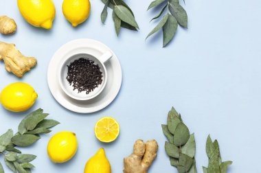 Creative food concept. Fresh ginger root, cup tea with brewing inside, lemon, eucalyptus leaves on blue background. Flat lay top view copy space. Minimalistic style seasoning spice ingredient for tea clipart