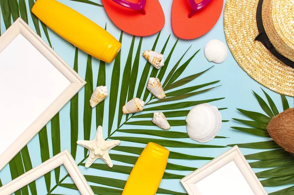 Yaz moda düz yatıyordu. Hasır şapka mercan parmak arası terlik tropikal palmiye yaprakları güneş kremi beyaz fotoğraf çerçevesi hindistan cevizi deniz kabukları mavi arka plan üzerinde denizyıldızı. En iyi görünüm kopyalama alanı. Yaratıcı tatil arka planı