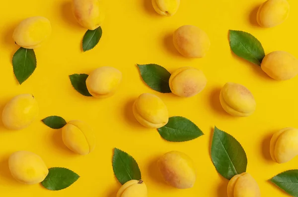 Rijpe verse abrikozen vruchten met groene bladeren op gele achtergrond. Platte lay, bovenaanzicht, kopieer ruimte. Verse biologische abrikozen, dieet veganistisch eten. Creatief abrikoos patroon. Oogst concept — Stockfoto