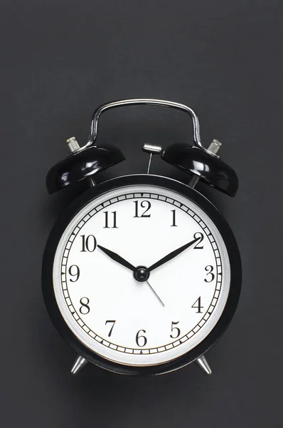 灰色の暗い背景上面フラットに黒のレトロな目覚まし時計には、コピー領域が横たわっていた。ミニマルな背景、朝仕事に時間、締め切り時間の概念 — ストック写真