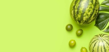 Olgun karpuz çileği, komple limon, yeşil arka planda tropikal yaprak canavarı düz zemin. Yeşil Çizgili Koca Karpuz. Yaz aydınlığı arka plan. Yaratıcı Minimum Meyve Konsepti