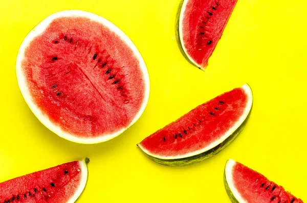 Half and pieces of ripe juicy red watermelon on bright yellow background. Flat lay, top view, copy space. Creative summer food concept — Stock Photo, Image