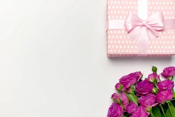Geschenkbox mit zartem Band und Strauß leuchtend rosa Rosen auf hellgrauem Hintergrund. flache Lage, Draufsicht, Kopierraum. Glückwunschkarte zum Geburtstag, Frauentag oder Muttertag. Zusammensetzung der Blumen — Stockfoto
