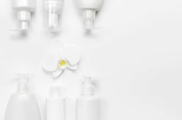 Белые пластиковые контейнеры для бутылок и орхидея цветок на белом фоне вид сверху плоский лежал. Косметика SPA брендинг макет, натуральная органическая косметика концепция продукта, минимализм стиль косметики — стоковое фото