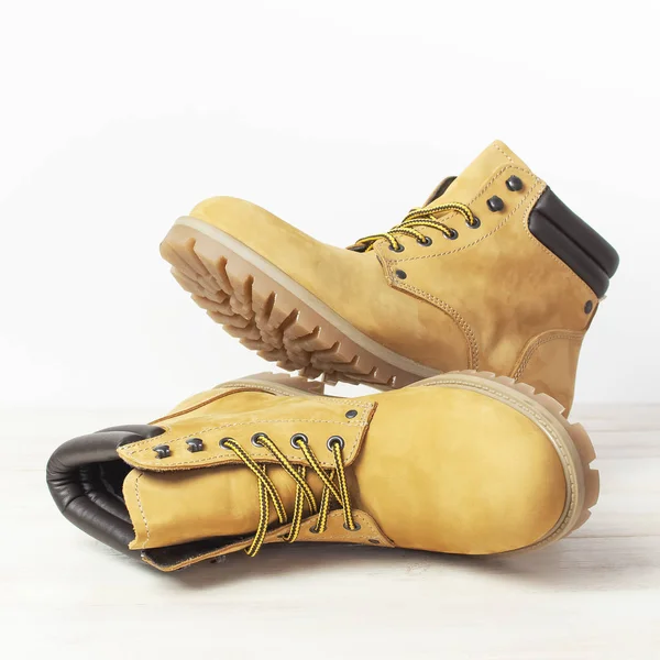 Κοντινό-up κίτρινων ανδρών εργασίας μπότες από φυσικό δέρμα nubuck σε ξύλινο λευκό φόντο. Μοντέρνα casual υποδήματα στυλ νεολαίας. Έννοια της διαφήμισης φθινόπωρο χειμερινά παπούτσια πώληση κατάστημα — Φωτογραφία Αρχείου