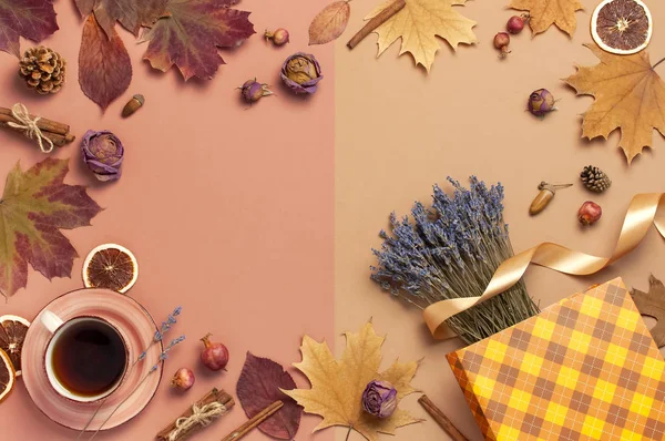 Autumn Flat lay composition. Cup of tea, autumn dry leaves, roses flowers, lavender, gift bag cones decorative pomegranate cinnamon sticks on brown pink background top view. Autumn, fall concept