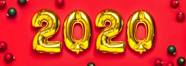 2020 inflatable golden numbers with red and green christmas balls on red background. Tahun baru dekorasi musim dingin, simbol liburan, barang pesta. Selamat kartu ucapan Natal. Selamat Tahun Baru. Letak rata — Stok Foto