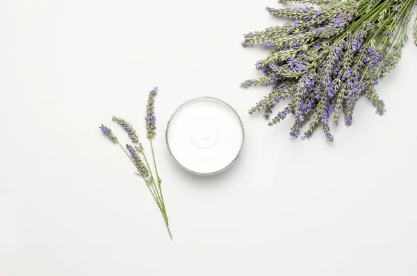 Concept of natural spa cosmetics. Open jar of hand, face or body cream and bouquet of lavender on white background top view copy space. Natural herbal skin care products