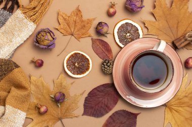 Sonbahar daire kompozisyon yatıyordu. Fincan çay, damalı ekose, sonbahar kuru yaprakları, gül çiçekleri, turuncu daire koni dekoratif nar tarçın kahverengi bej arka plan üst görünümünde sopa. Sonbahar konsepti