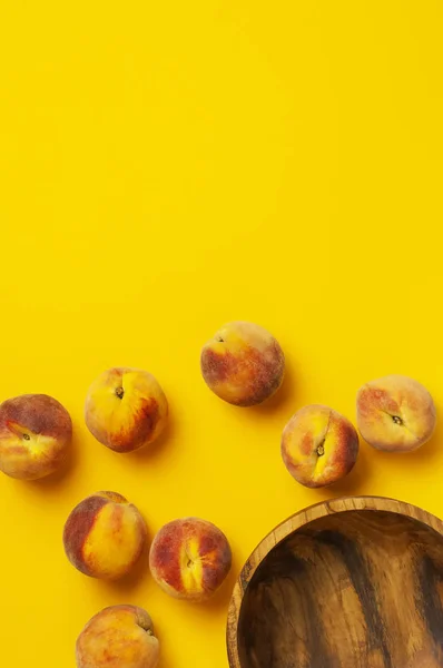 Плоская композиция с персиками. Спелые сочные персики в деревянной чаше на желтом фоне. Плоская лежала, вид сверху, копировальное пространство. Свежие органические фрукты, веганская еда. Концепция сбора урожая — стоковое фото