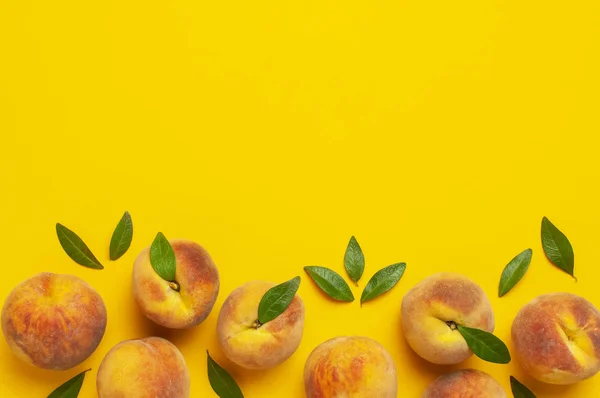 Плоская композиция с персиками. Спелые сочные персики с зелеными листьями на желтом фоне. Плоская лежала, вид сверху, копировальное пространство. Свежие органические фрукты, веганская еда. Концепция сбора урожая — стоковое фото