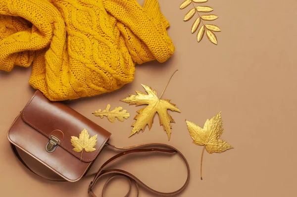 Brown leather women bag, orange knitted sweater, golden autumn leaf on brown background top view flat lay copy space. Fashionable women's accessories. Autumn Fashion Concept. Stylish Lady Clothes — Stock Photo, Image