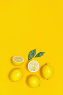 Olgun sulu limon ve parlak sarı zemin üzerine yeşil yaprakları. Limon meyve, narenciye en az kavramı, vitamin C. yaratıcı yaz yiyecek minimalist arka plan. Düz yatıyordu, en iyi görünüm, kopya alanı