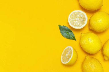Olgun sulu limon ve parlak sarı zemin üzerine yeşil yaprakları. Limon meyve, narenciye en az kavramı, vitamin C. yaratıcı yaz yiyecek minimalist arka plan. Düz yatıyordu, en iyi görünüm, kopya alanı